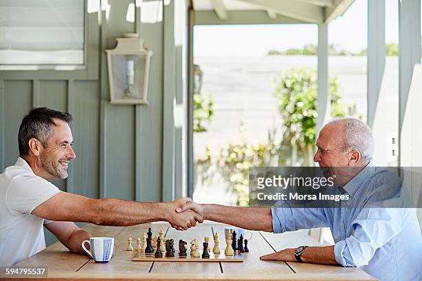 father and son shaking hands over chess set - the short game stock pictures, royalty-free photos & images