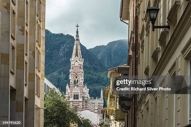 stripe spire of el carmen church as veiwed from narrow streets in la candelaria neighborhood in bogota, colombia - bogota colombia stock pictures, royalty-free photos & images