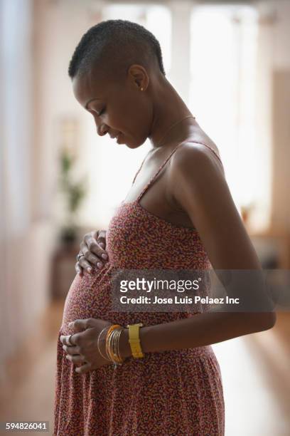 black woman rubbing her pregnant belly - belly rub stockfoto's en -beelden
