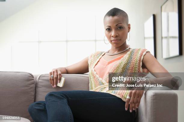serious black woman sitting on sofa - attitude stock pictures, royalty-free photos & images