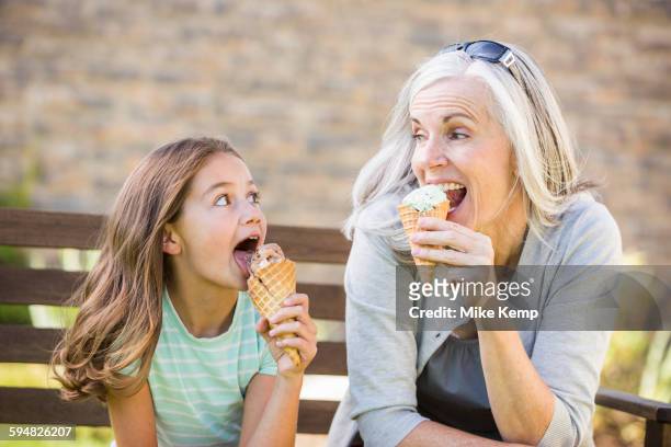 caucasian grandmother and granddaughter eating ice cream - girls licking girls stockfoto's en -beelden
