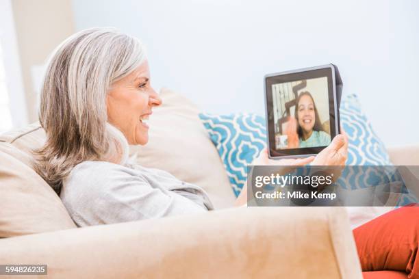 caucasian grandmother videochatting with granddaughter on digital tablet - lehi stock pictures, royalty-free photos & images