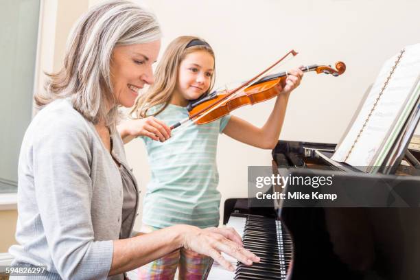 caucasian grandmother and granddaughter playing music together - playing music photos et images de collection