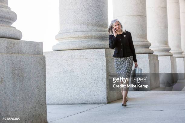 caucasian businesswoman talking on cell phone under columns - politicians female stock pictures, royalty-free photos & images