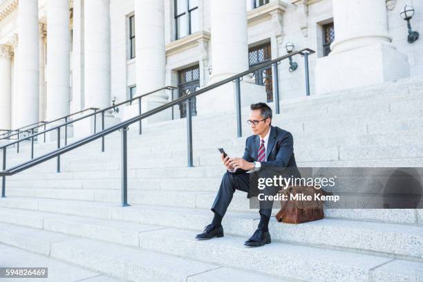 mixed race businessman using cell phone on courthouse steps - people associated with politics & government stock pictures, royalty-free photos & images