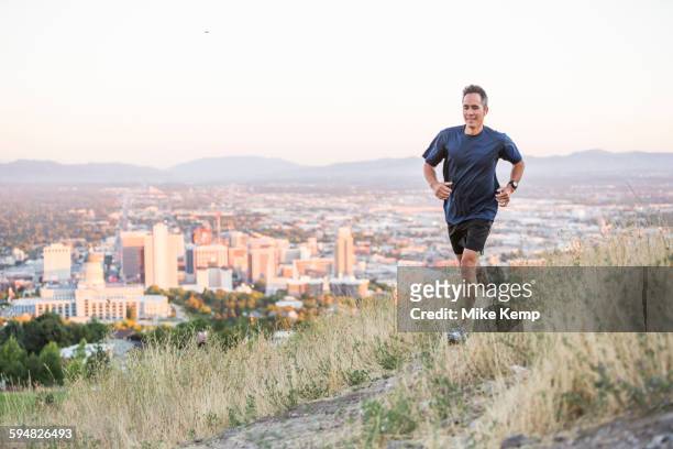 mixed race man running on hilltop over salt lake city, utah, united states - salt lake city stock pictures, royalty-free photos & images