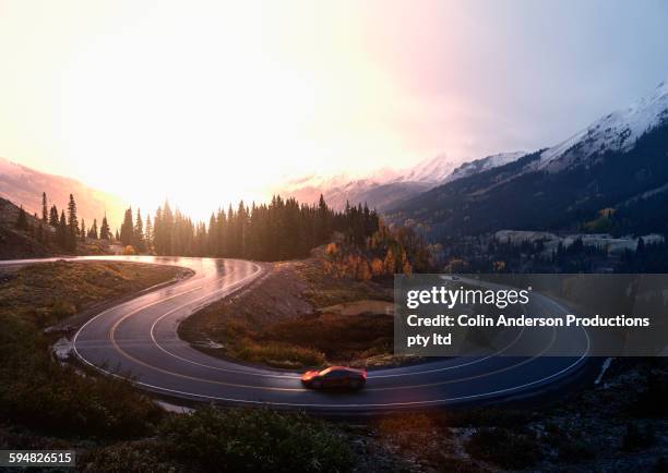 sports car driving on winding remote road - car on road stock pictures, royalty-free photos & images