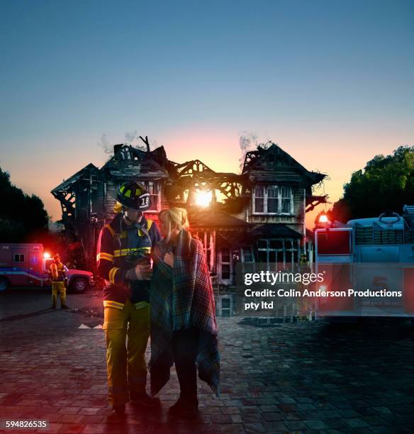 caucasian firefighter comforting woman at burned house - australia fire - fotografias e filmes do acervo