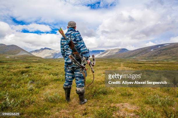 mari hunter carrying crossbow in remote field - crossbow ストックフォトと画像