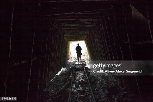 mari man walking on tracks in mine - mijnwerker stockfoto's en -beelden
