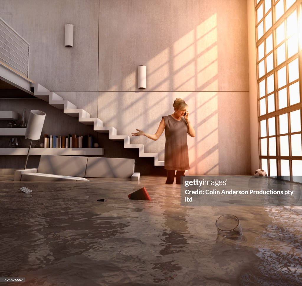 Caucasian woman talking on cell phone in flooded house