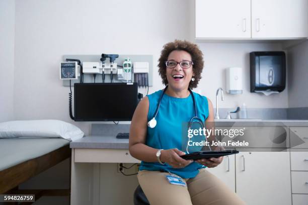 african american doctor holding digital tablet - black female doctor stock-fotos und bilder