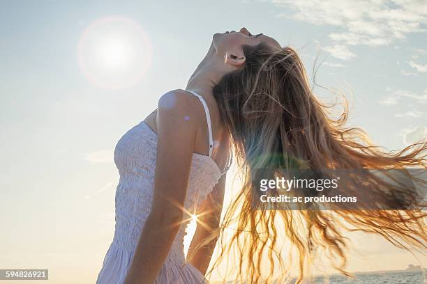 caucasian woman tossing her hair outdoors - human hair stockfoto's en -beelden