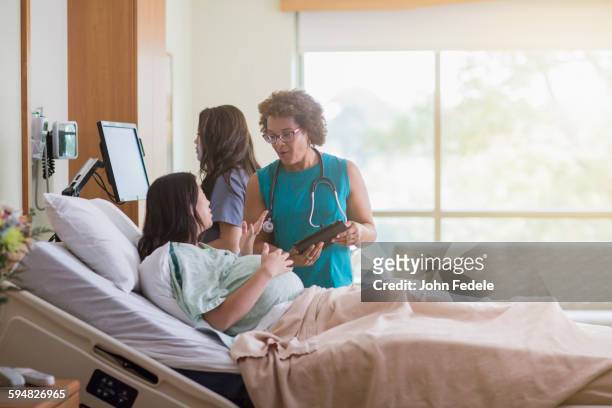 doctor talking to pregnant patient in hospital room - maternity ward stock pictures, royalty-free photos & images