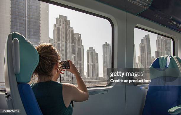 caucasian woman photographing dubai cityscape on train, dubai emirate, united arab emirates - dubai tourism stock pictures, royalty-free photos & images