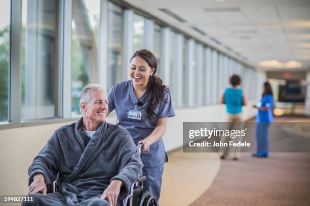 nurse pushing patient in wheelchair - rollstuhl schieben stock-fotos und bilder