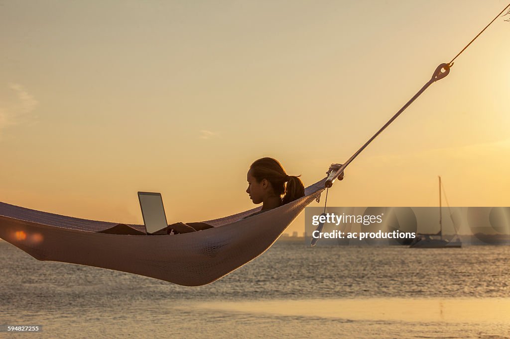 Caucasian woman using laptop in hammock