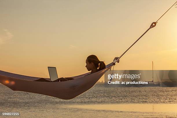 caucasian woman using laptop in hammock - time off work stock pictures, royalty-free photos & images