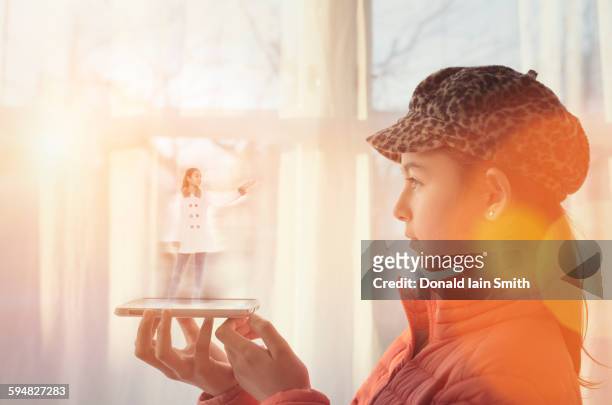 mixed race girl examining hologram projection - smartphone hologram stockfoto's en -beelden