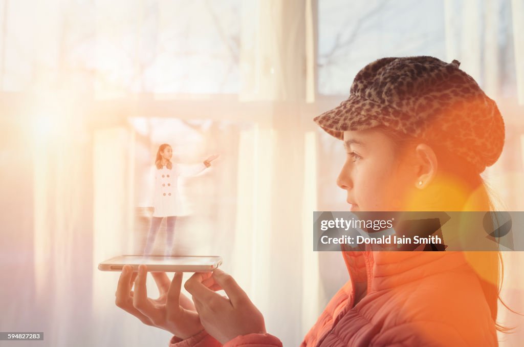 Mixed race girl examining hologram projection