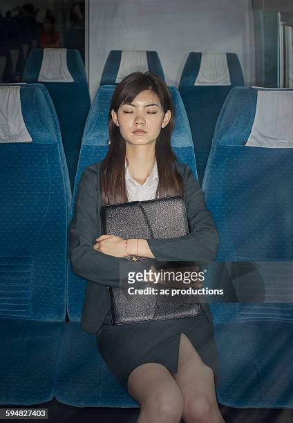 chinese businesswoman napping on airplane - ac weary stockfoto's en -beelden