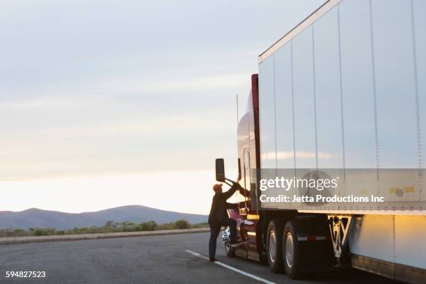 caucasian man climbing into truck on highway - old truck stock-fotos und bilder