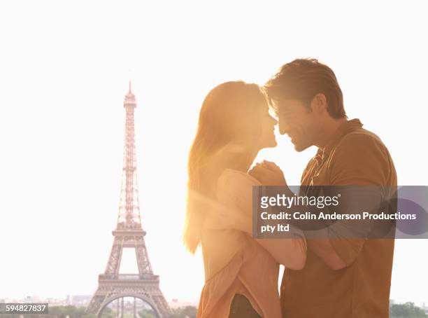 hispanic couple hugging at eiffel tower, paris, ile - couple paris stock-fotos und bilder
