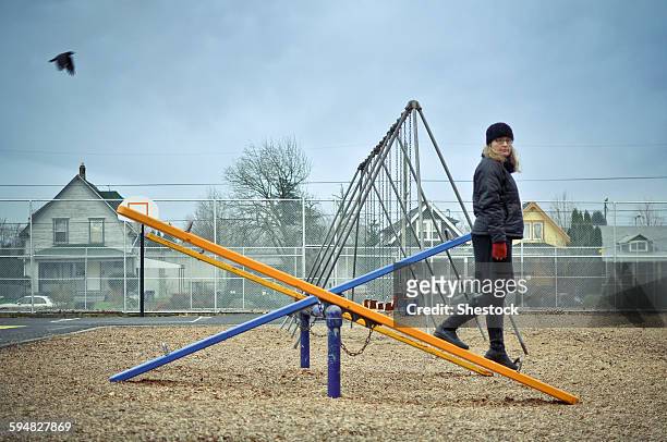 caucasian woman walking on playground seesaw - see saw fotografías e imágenes de stock
