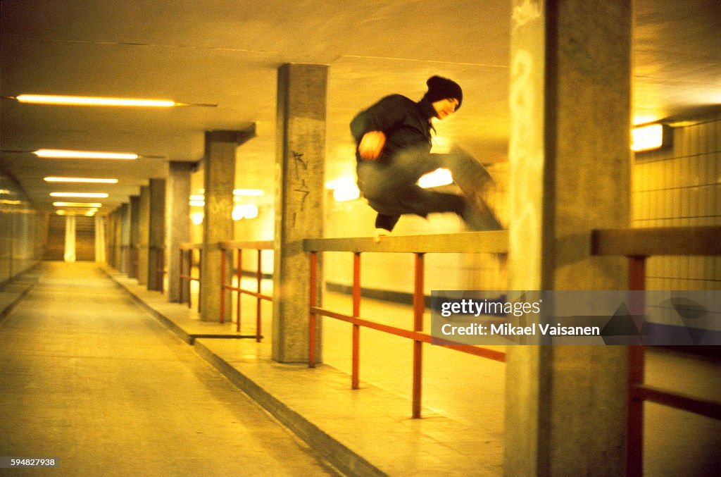 A young man who is jumping over a railing, subway