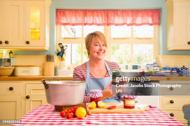 caucasian woman making jam in kitchen - marmelade machen stock-fotos und bilder