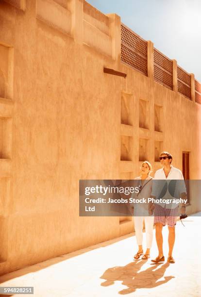 caucasian couple walking under wall - dubai travel stock-fotos und bilder