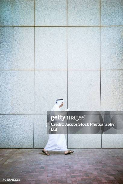 middle eastern architect carrying blueprints - arab man walking stock pictures, royalty-free photos & images