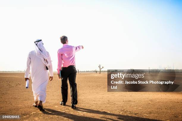 businessmen walking in desert - emirati at work stock-fotos und bilder