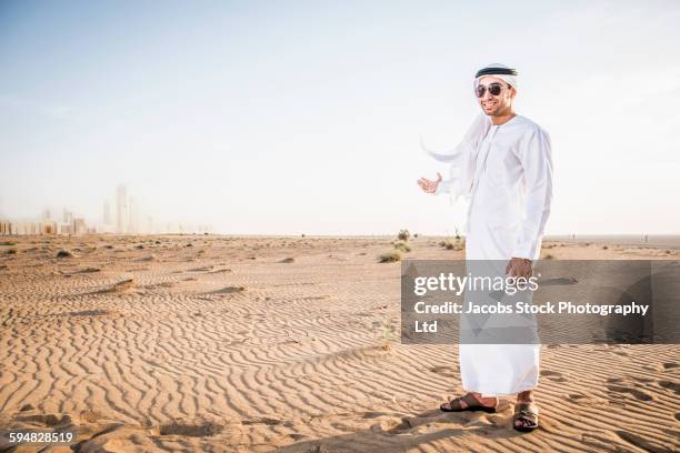 middle eastern man standing in desert - emirati enjoy stock-fotos und bilder