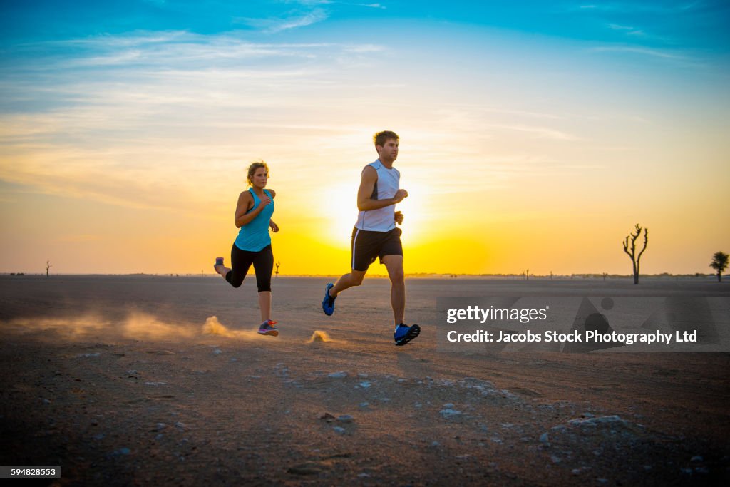 Caucasian couple running in desert
