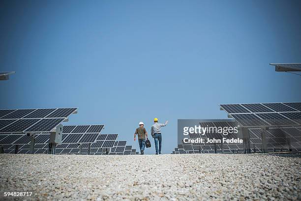 Caucasian technicians talking near solar panels