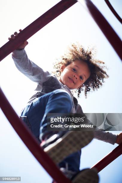 low angle view of mixed race boy climbing on play structure - kid looking up to the sky imagens e fotografias de stock