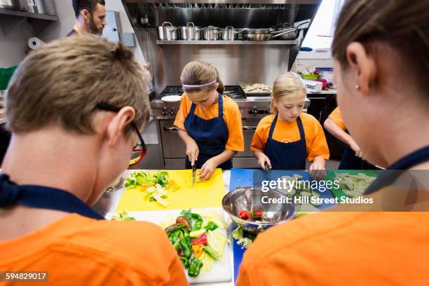 students chopping vegetables in cooking class - cours de cuisine photos et images de collection