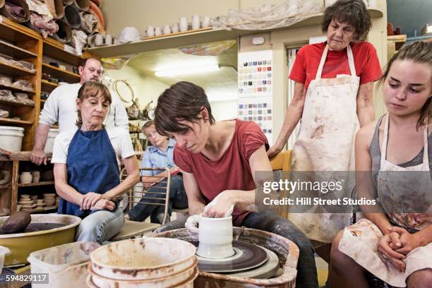 teacher demonstrating pottery wheel for students - woman pottery wheel stock pictures, royalty-free photos & images