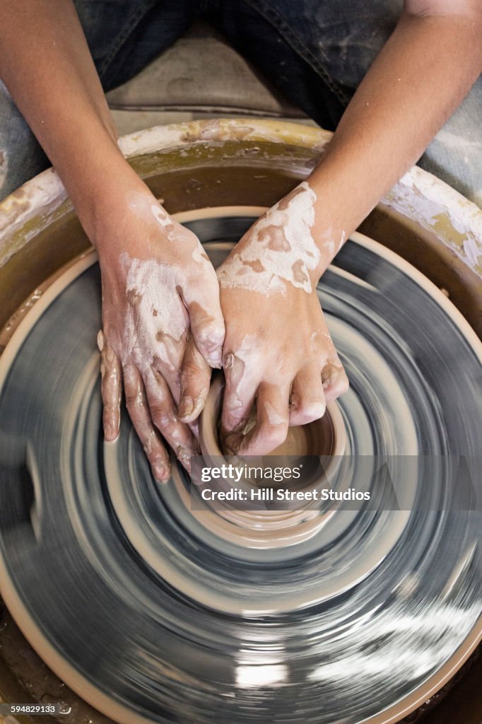 Artist shaping pottery on wheel