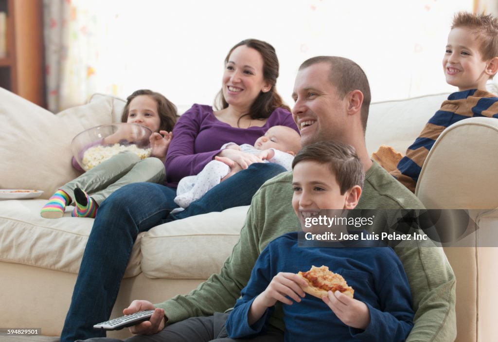 Caucasian family watching television in living room