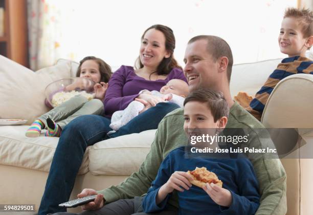 caucasian family watching television in living room - fyrbarnsfamilj bildbanksfoton och bilder