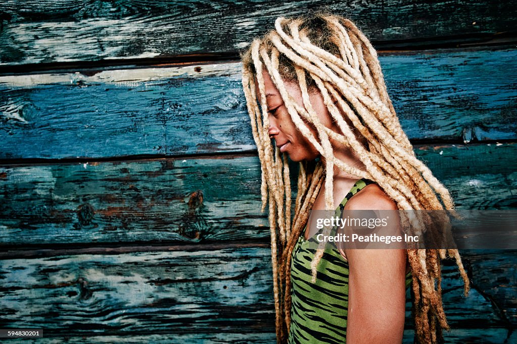 Black woman with dreadlocks at wooden wall