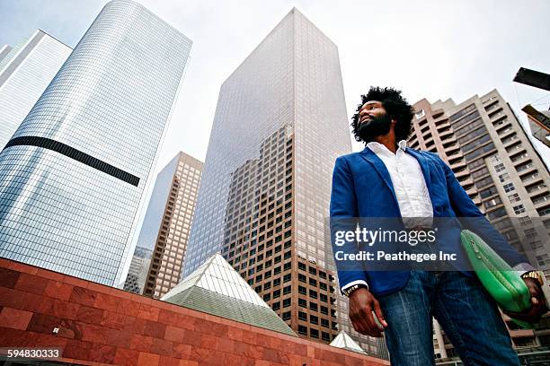 mixed race businessman walking under skyscrapers - low angle view man stock pictures, royalty-free photos & images