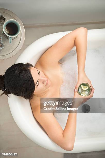 woman drinking cocktail in bubble bath - badewanne mit obst stock-fotos und bilder