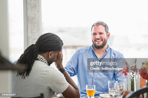 men laughing at dinner table - hands on face stock-fotos und bilder