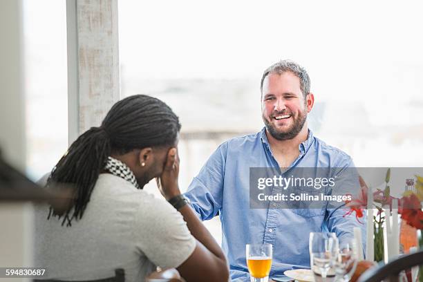 men laughing at dinner table - kopf in den händen stock-fotos und bilder