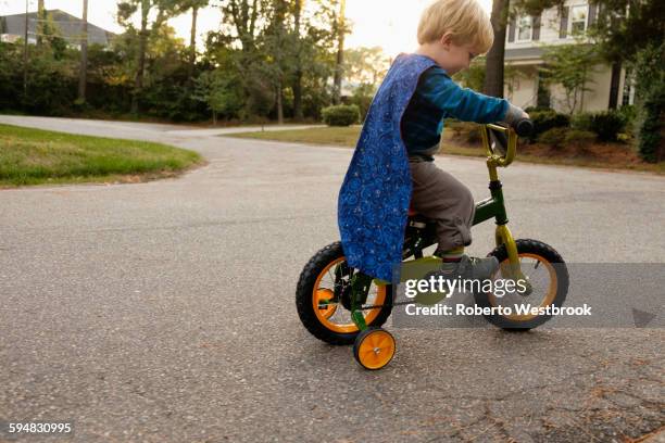 caucasian boy riding bicycle with training wheels - training wheels stock pictures, royalty-free photos & images
