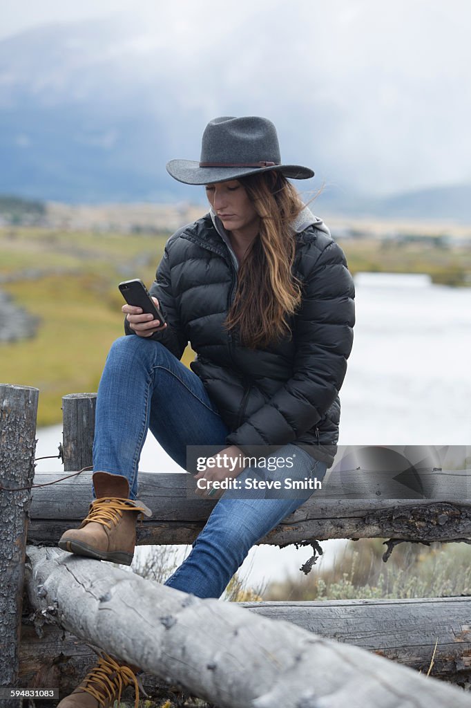 Caucasian woman using cell phone at rural river