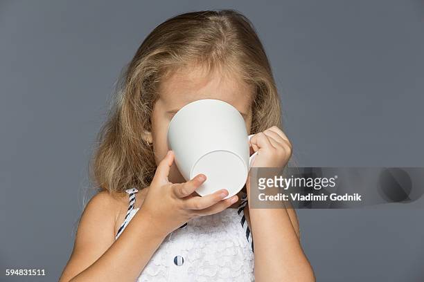 girl drinking coffee against gray background - obscured face stock-fotos und bilder